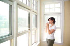 A Woman Looks Out Through a Wall of Attractive Double-Hung Windows
